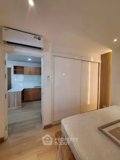 Modern bedroom with sliding closet doors and view into a stylish kitchen