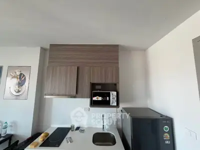 Modern kitchen with sleek cabinetry, built-in microwave, and compact fridge in a stylish apartment.