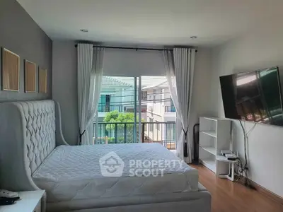 Bright bedroom with large window and modern decor, featuring a comfortable bed and wall-mounted TV.