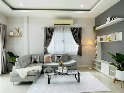 Modern living room with stylish decor, featuring a cozy gray sectional sofa, elegant curtains, and ambient lighting.