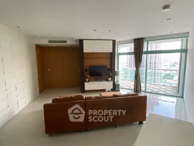 Spacious living room with modern decor and large balcony offering city views.