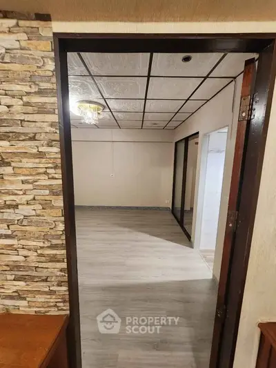 Spacious empty room with modern flooring and stone accent wall, ready for customization.