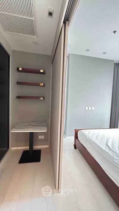 Modern bedroom with sleek design and minimalist decor, featuring a cozy bed and stylish shelving.
