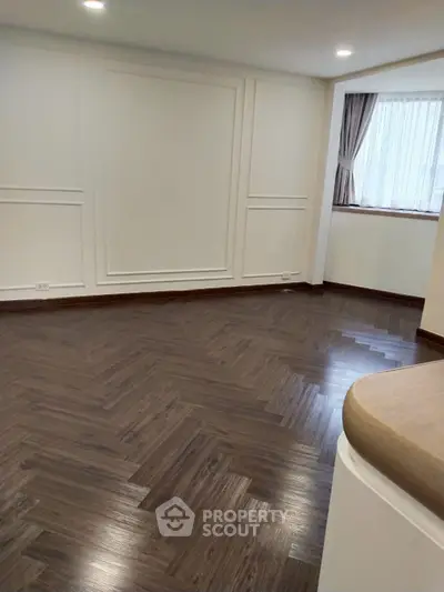 Spacious modern living room with elegant wood flooring and large window.