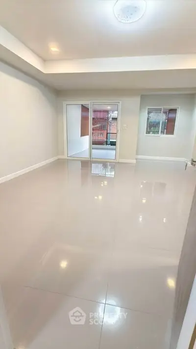 Spacious empty room with glossy tiled floors and large windows for natural light.