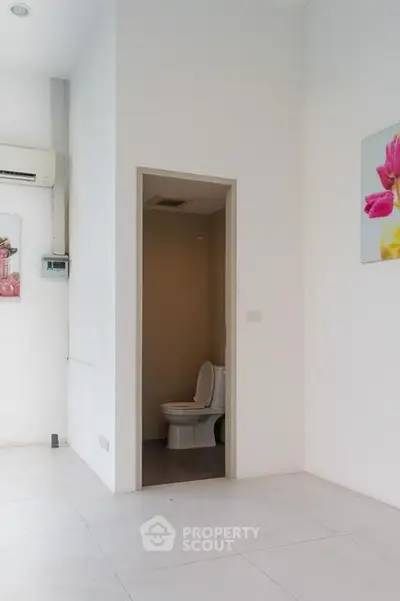 Minimalist bathroom with white walls and modern toilet in a bright space.