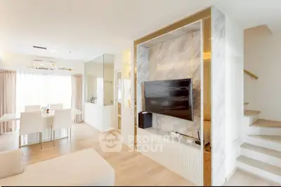 Modern open-plan living room with sleek TV setup and dining area