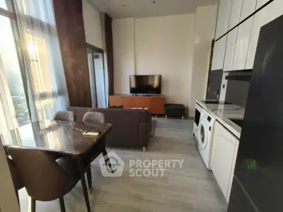 Modern living room with dining area and washing machine, featuring sleek furniture and large windows.