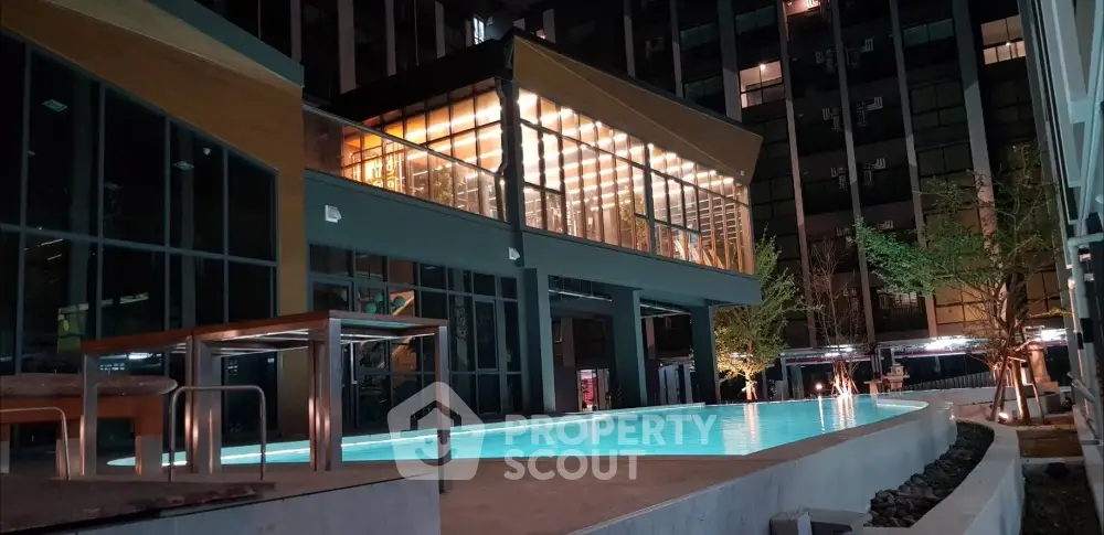 Luxurious modern building with illuminated pool at night, perfect for upscale living.