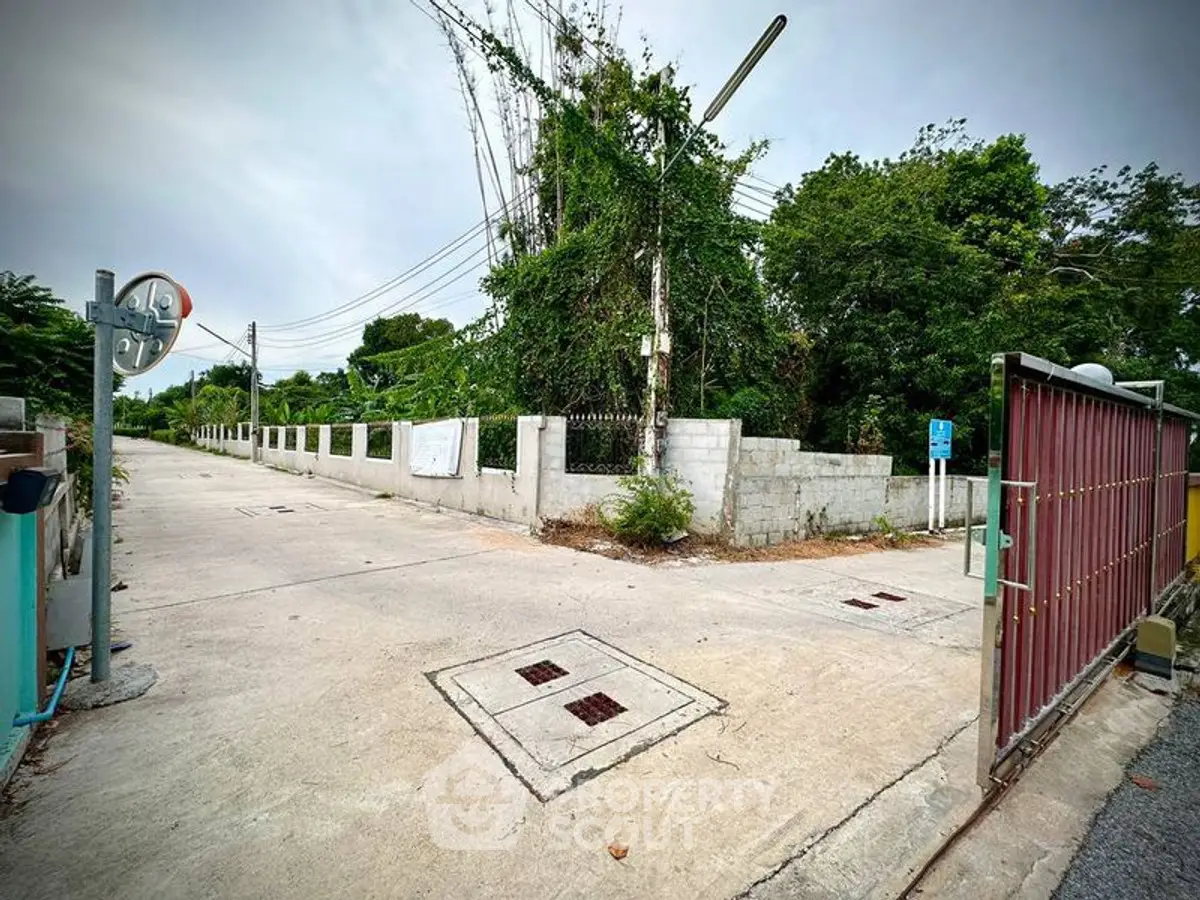 Spacious corner lot with lush greenery and secure gated entrance, ideal for development.