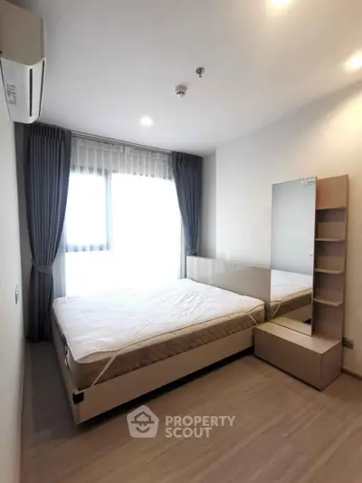 Modern bedroom with large window and stylish decor in a contemporary apartment.