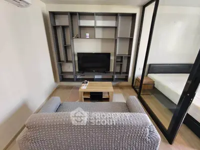 Modern living room with sleek shelving and cozy sofa, adjacent to a glass-walled bedroom.