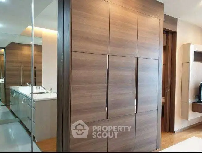 Modern interior with sleek wooden cabinetry and mirrored accents in a stylish home setting.