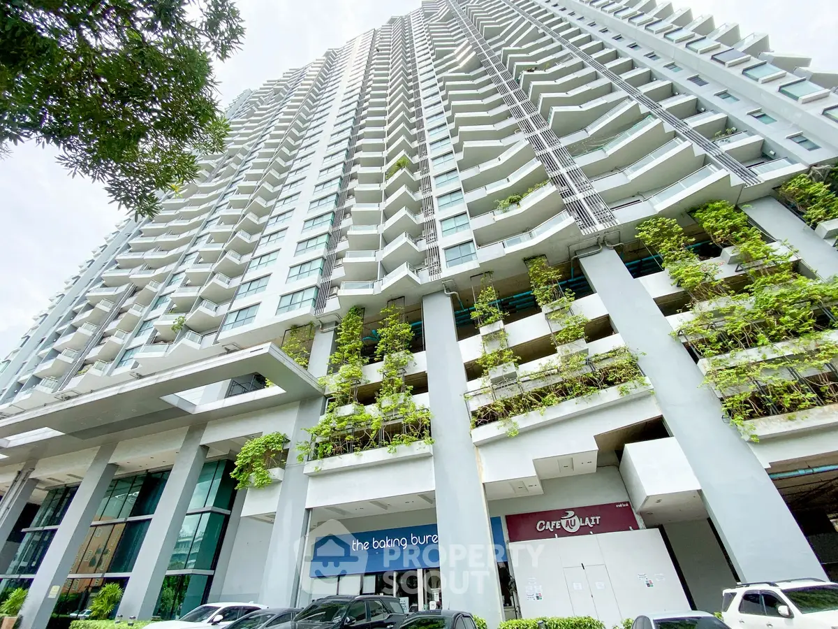 Modern high-rise building with lush greenery and commercial spaces at the base, offering urban living.