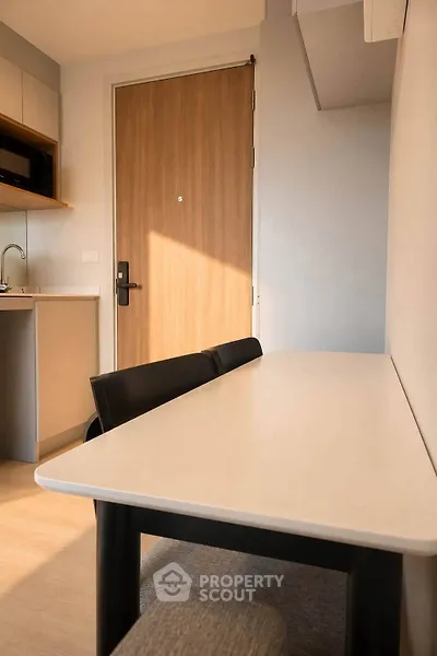 Modern apartment interior with sleek kitchen and dining area, featuring minimalist design and warm lighting.