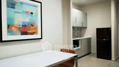 Modern kitchen with sleek cabinets and abstract art in a cozy apartment setting.