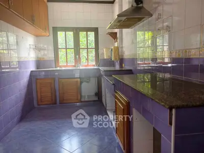 Charming kitchen with vibrant purple tiles and natural light through large windows.