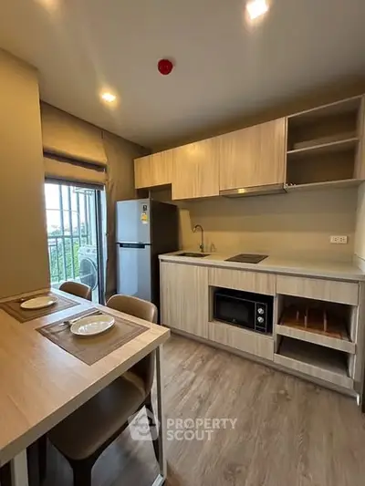 Modern kitchen with sleek cabinets and dining area in cozy apartment