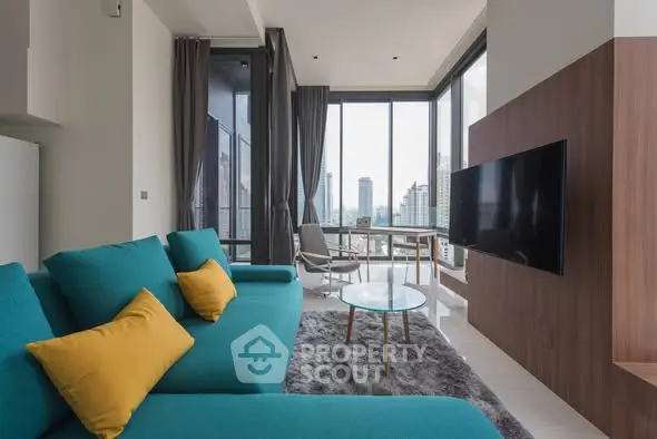 Modern living room with city view, featuring teal sofa and large windows.
