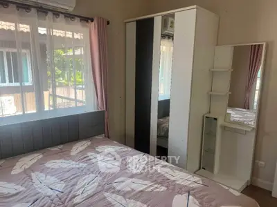Cozy bedroom with stylish decor and ample natural light, featuring a mirrored wardrobe and elegant bedding.