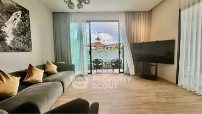Modern living room with large TV and balcony view, featuring elegant decor and natural light.