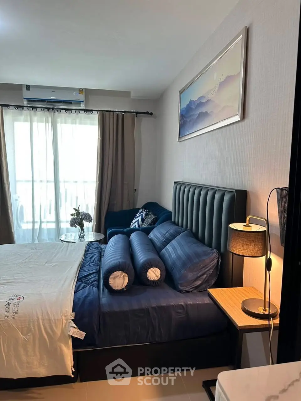 Cozy bedroom with modern decor and natural light from large window.