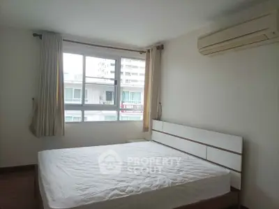 Spacious bedroom with large window and air conditioning in modern apartment.