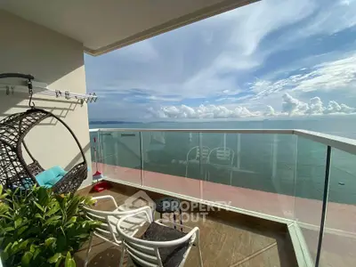 Stunning ocean view from a modern balcony with cozy seating and hanging chair.