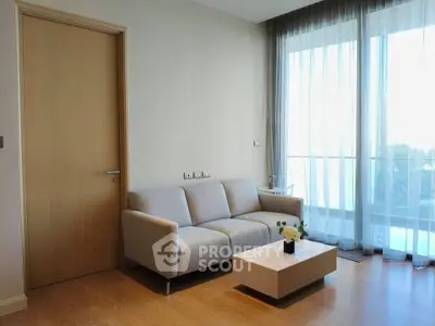 Modern living room with cozy sofa and natural light from large windows.