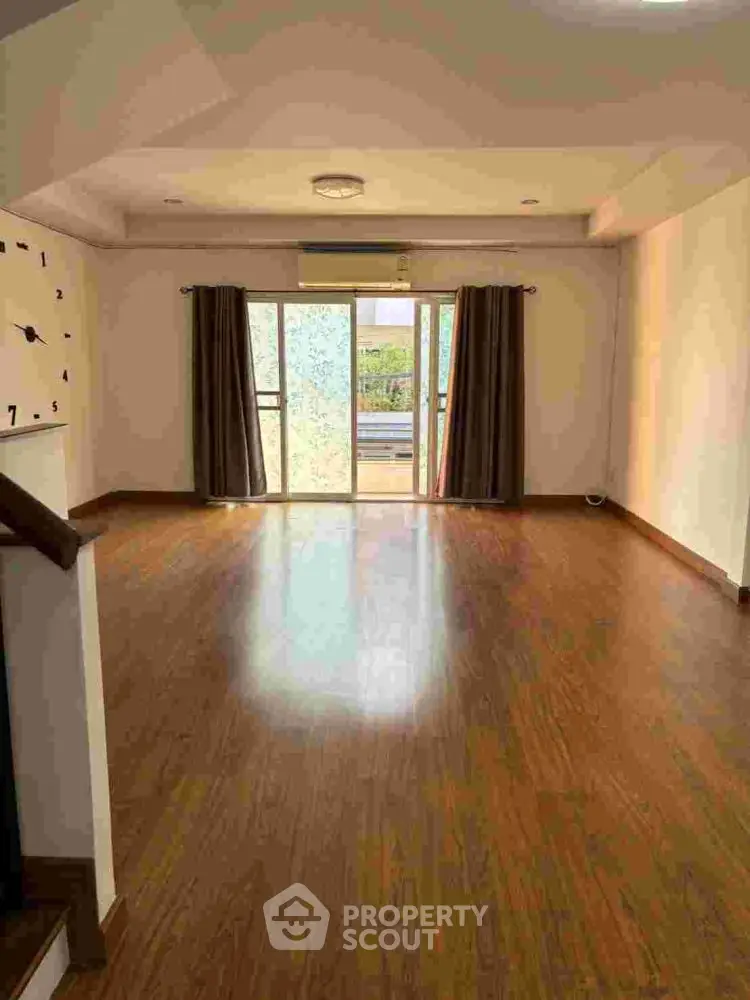 Spacious living room with wooden flooring and large windows for natural light.