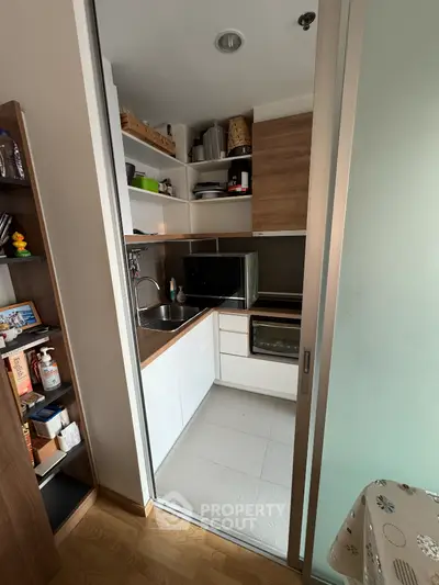 Compact modern kitchen with sleek cabinetry and built-in appliances in cozy apartment.