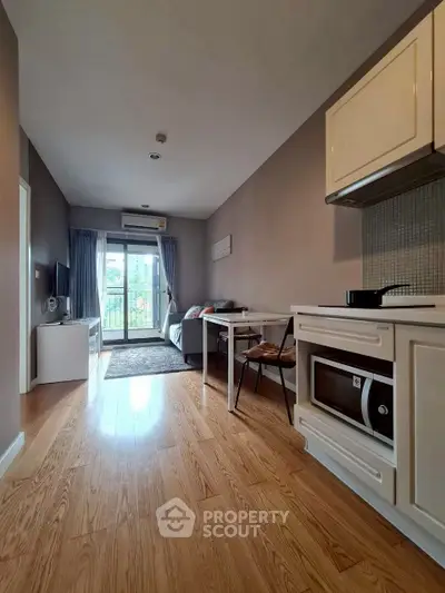 Modern open-plan living room with kitchen, wooden flooring, and balcony view.