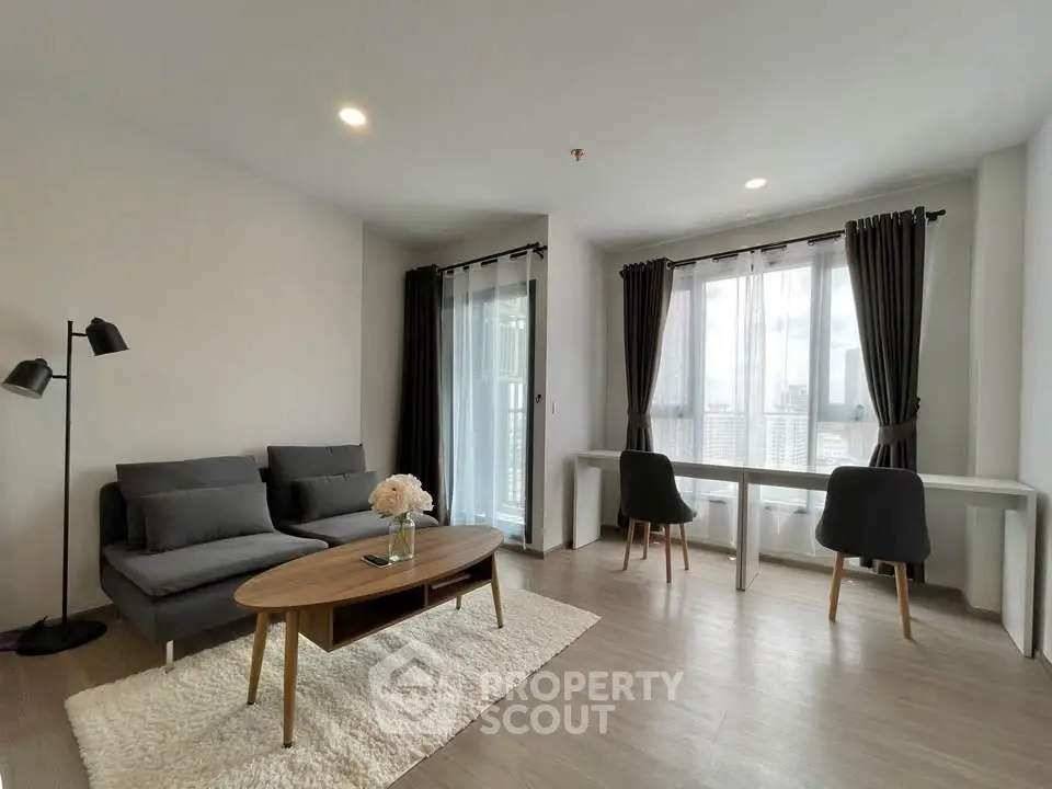 Modern living room with stylish furniture and large windows offering city views.