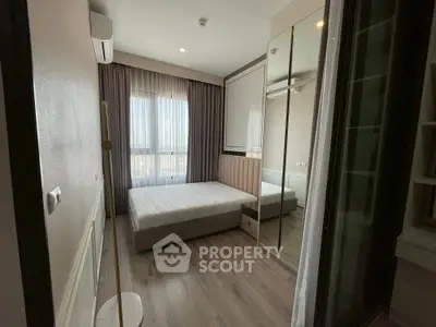 Modern bedroom with large window and mirrored wardrobe in stylish apartment.