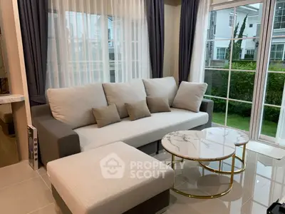 Elegant living room with modern sofa and marble coffee table, featuring large windows and garden view.