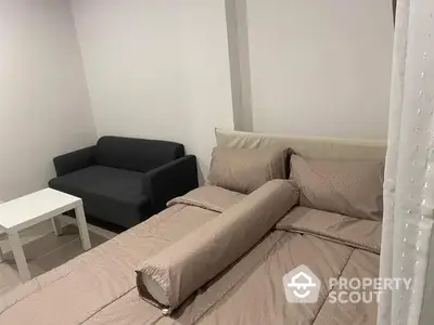 Cozy and compact bedroom with a comfortable bed, modern sofa, and a neat white coffee table, perfect for urban living.