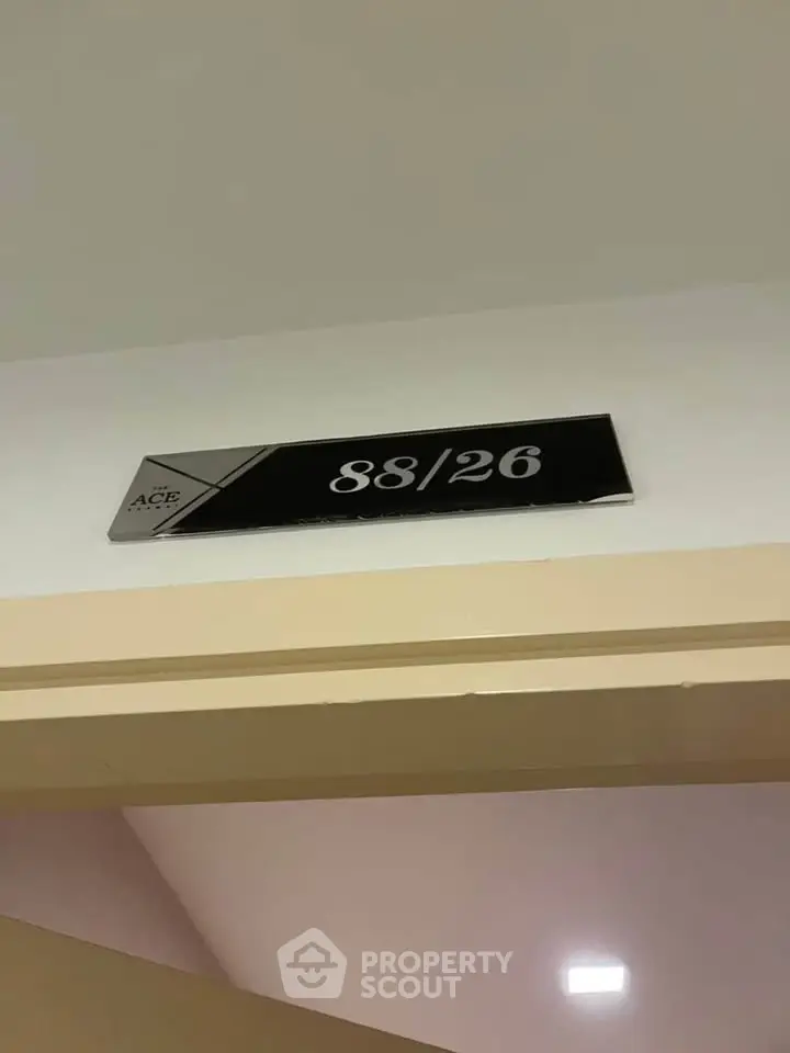 Modern apartment unit number sign on wall above doorway, sleek design.