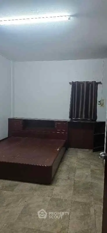 Spacious bedroom with wooden bed frame and tiled flooring, perfect for cozy living.
