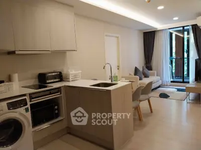 Modern open-plan kitchen and living area with sleek appliances and cozy seating.