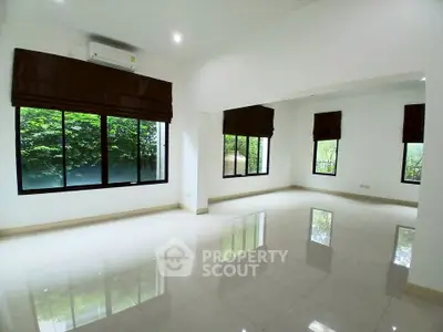 Spacious empty living room with large windows and glossy tiled floors, offering abundant natural light.