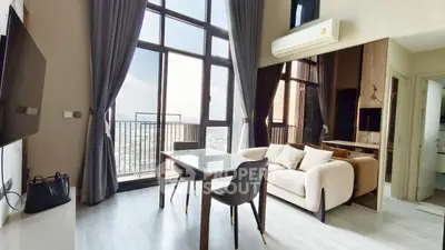 Modern living room with large windows and city view, featuring stylish furniture and sleek flooring.