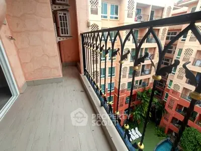 Charming balcony with intricate railing overlooking a vibrant courtyard and pool in a stylish apartment complex.