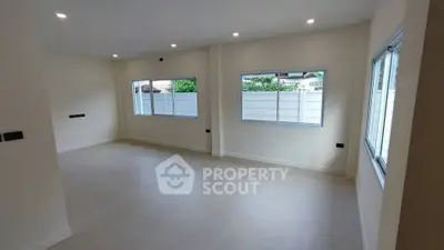 Spacious empty room with large windows and modern lighting