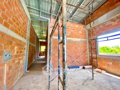 Spacious under-construction property with exposed brick walls and metal roofing, offering potential for customization.