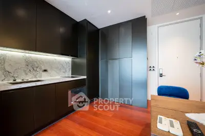 Modern kitchen with sleek black cabinets and marble backsplash in luxury apartment.
