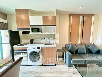 Modern kitchen with washing machine and cozy living area in open layout apartment.