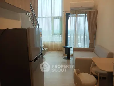 Modern living room with high ceilings, large windows, and cozy furniture in a stylish apartment.