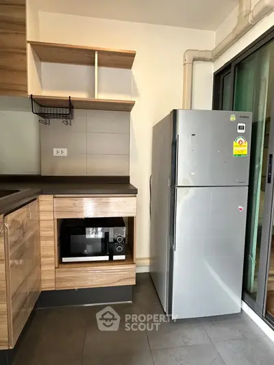 Modern kitchen with sleek cabinets, built-in microwave, and stainless steel fridge.