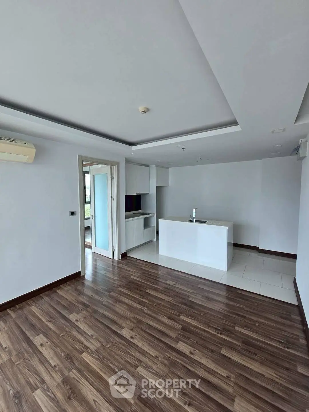 Modern open-plan living room with sleek wooden flooring and minimalist kitchen design.