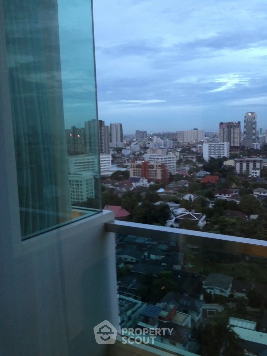 Stunning cityscape view from a high-rise balcony, showcasing urban skyline and lush greenery.